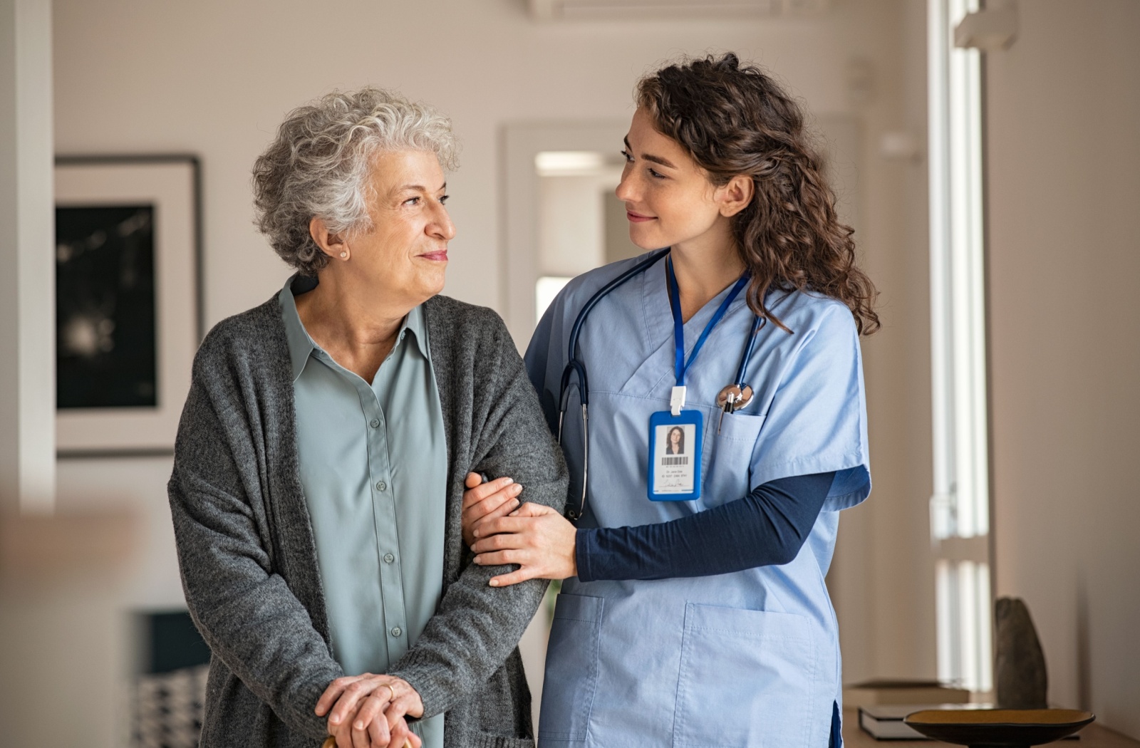 An older woman is being accompanied to her care regime by her nurse.