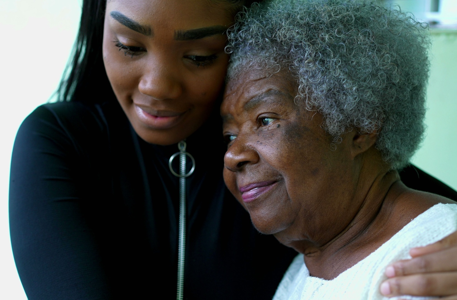 An adult daughter hugging her senior mother who she provides full time caregiving for.