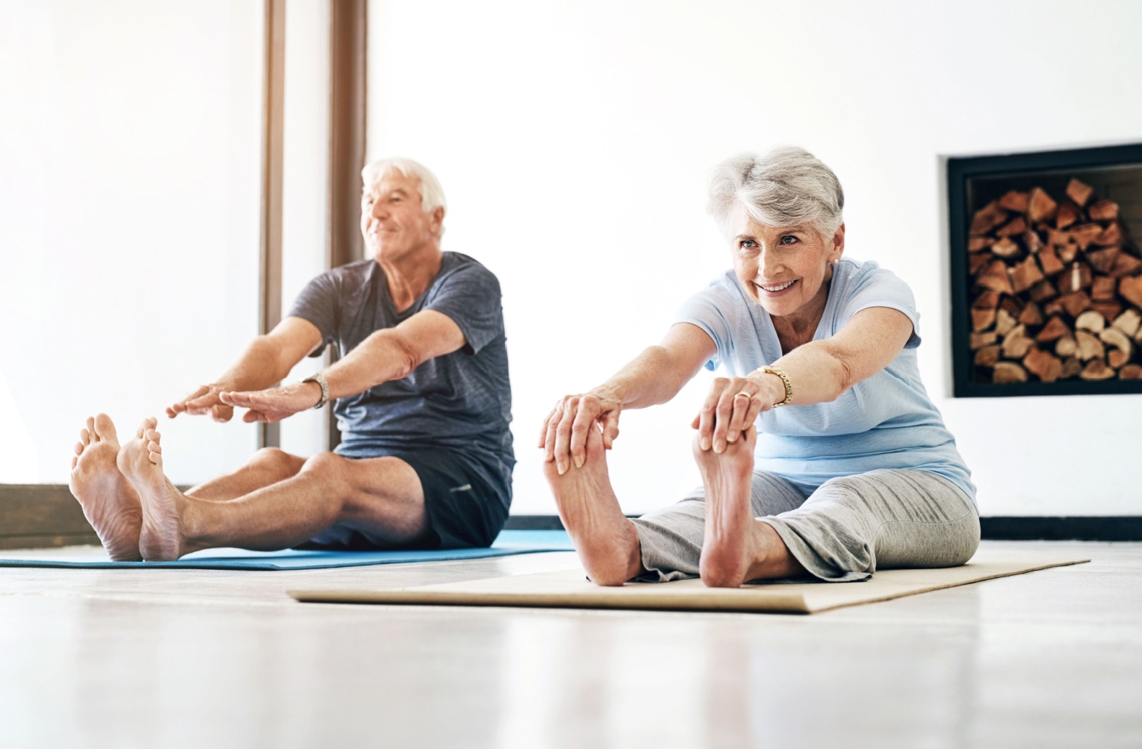 A senior couple doing some stretches together on yoga mats.