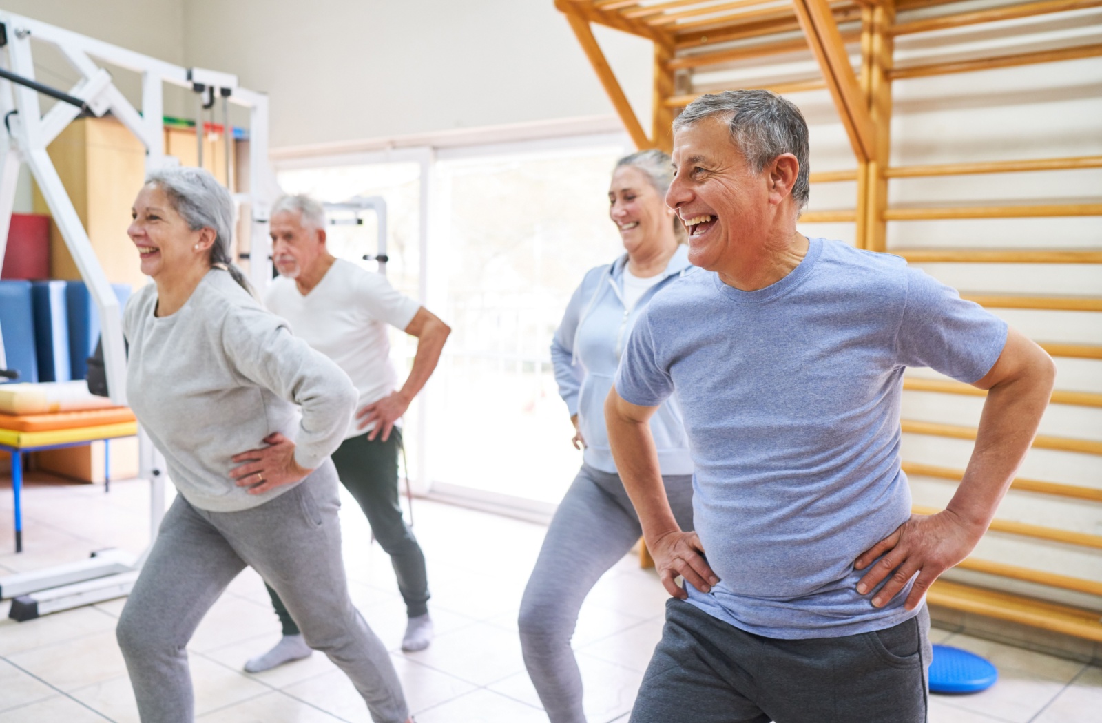 Group of happy seniors doing hip exercises.