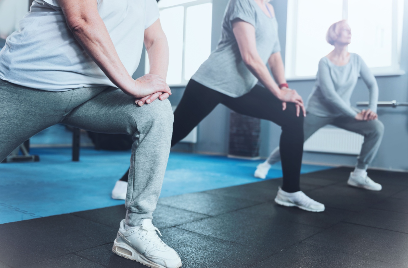 Three seniors stretch their legs during an exercise class offered by senior living to help promote joint health and fitness