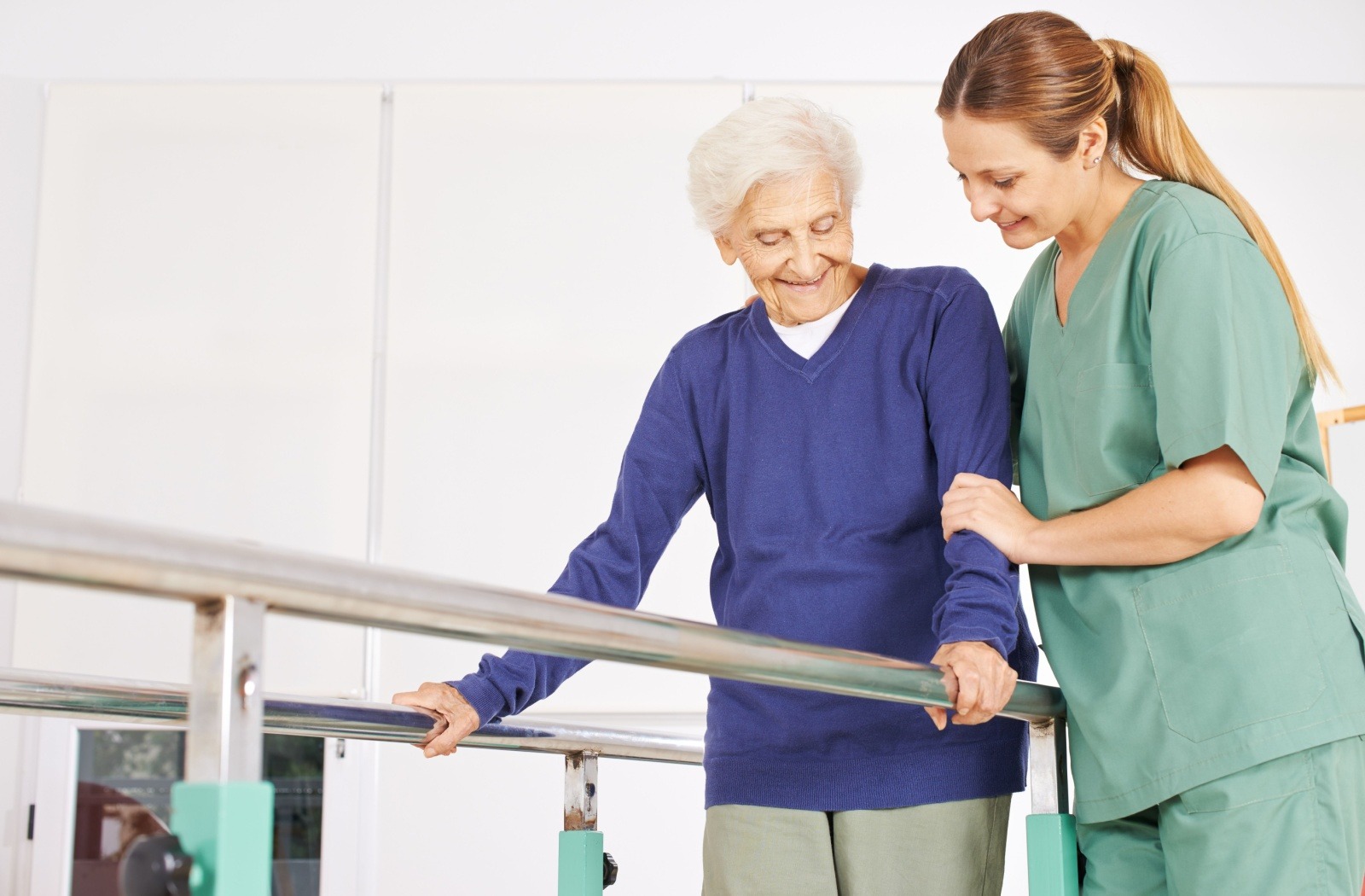 A senior holds onto balance bars with assistance from an occupational therapist.