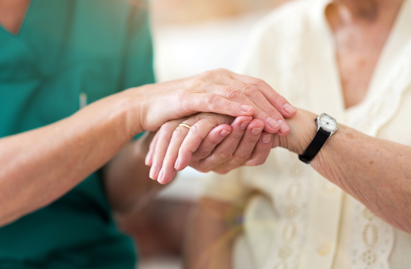 A caregiver holds hands with a senior in respite care.