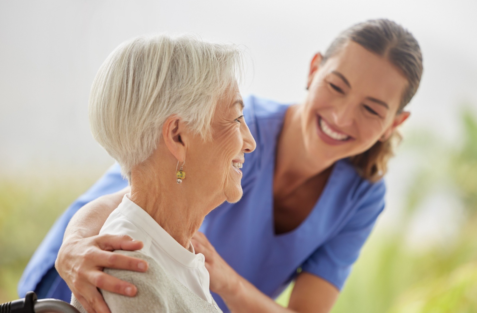A caregiver embraces a sitting senior in respite care.