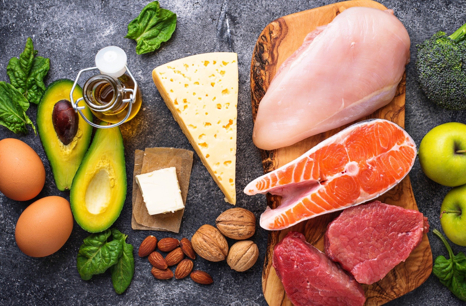 A selection of high-protein, nutritious foods, including chicken, salmon, avocado, nuts, eggs, fruit, etc.